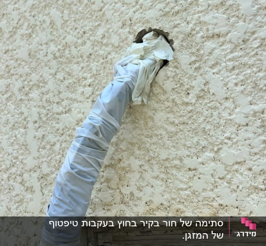 צנרת מזגן מבודדת היוצאת מתוך קידוח בקיר חיצוני